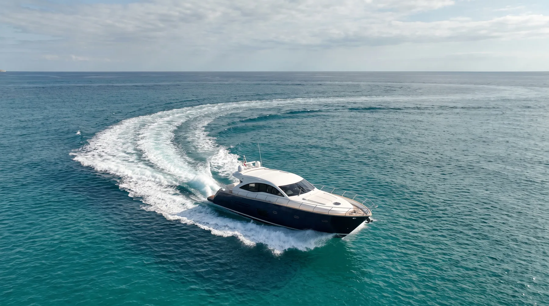 Navy-hulled yacht carving through turquoise water