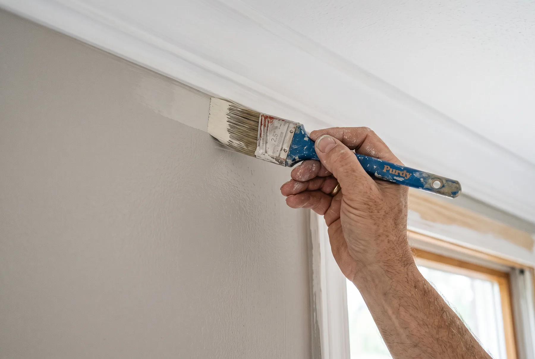 A painter cutting a clean edge along a wall